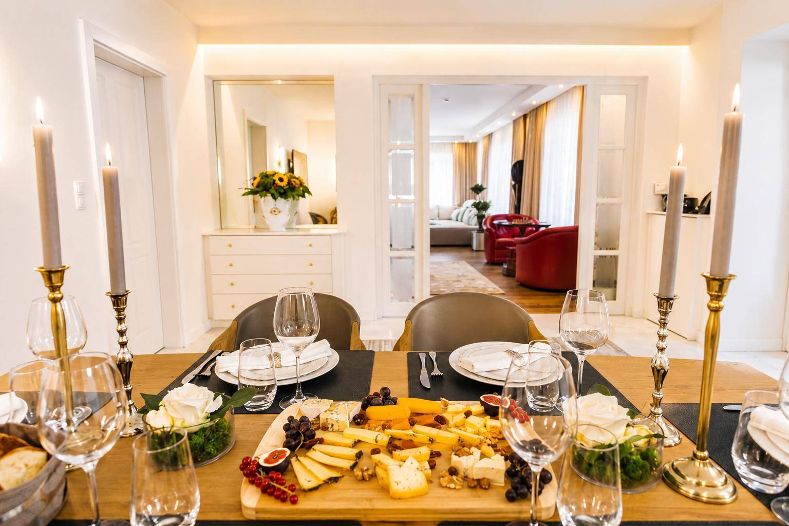 Elegant gedeckter Esstisch mit Käseplatte und Kerzen, angrenzend an einen Wohnbereich.