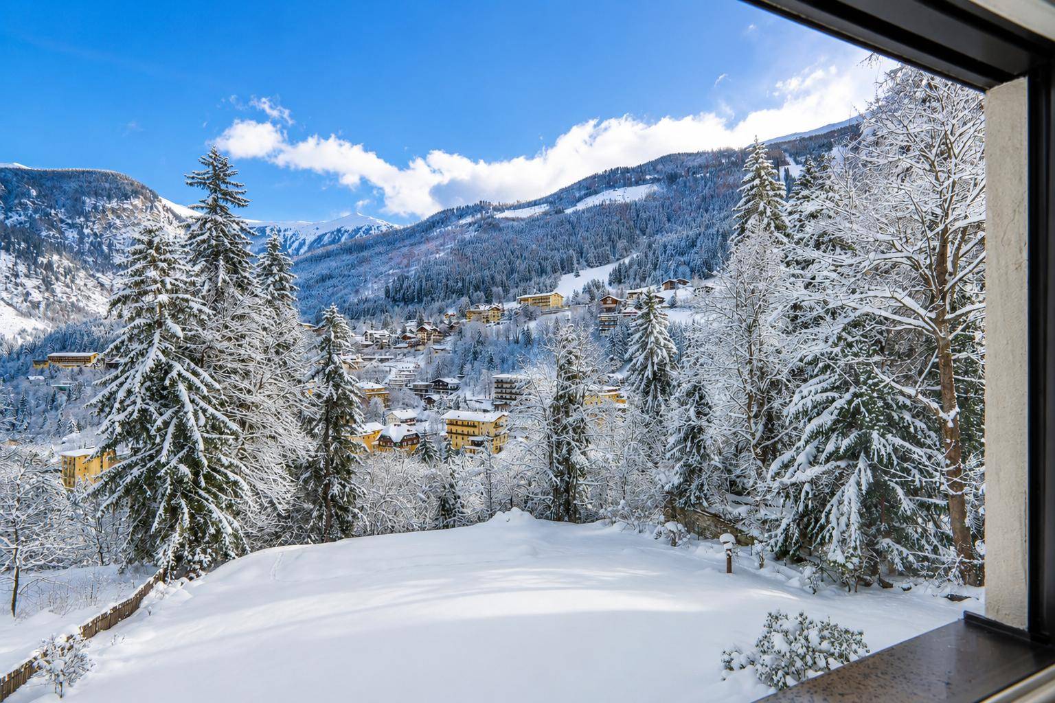 Malerischer Ausblick auf eine verschneite Berglandschaft mit Tannenbäumen und einem Dorf im Tal.