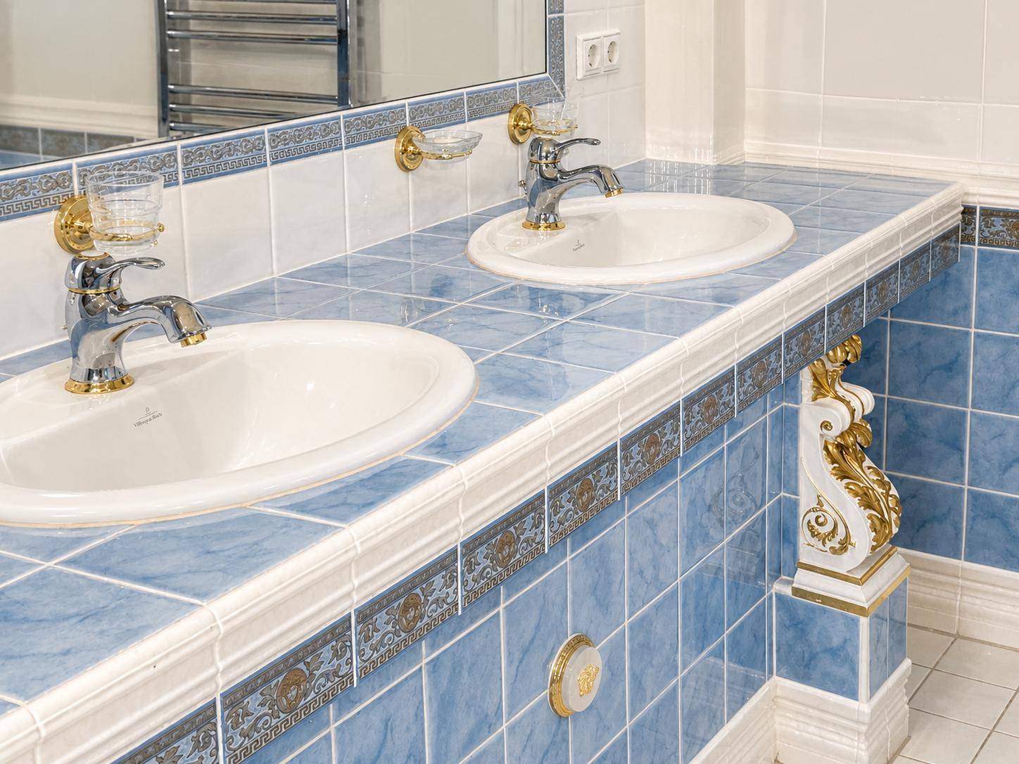 Badezimmer mit doppelten Waschbecken, blauen Fliesen und goldenen Armaturen im klassischen Stil.
