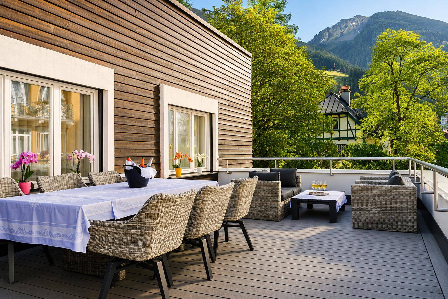 Geräumige Terrasse mit Esstisch und Lounge-Bereich, umgeben von grünen Bergen.