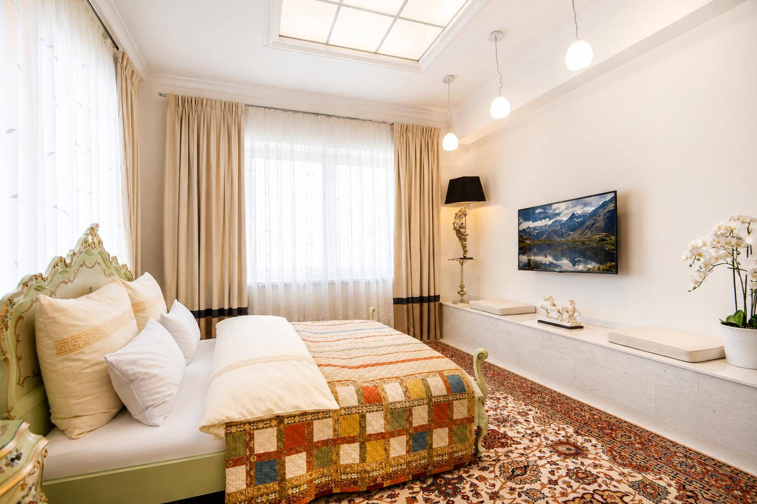 Elegantes Schlafzimmer mit opulentem Bett, Teppichboden und Deckenbeleuchtung.