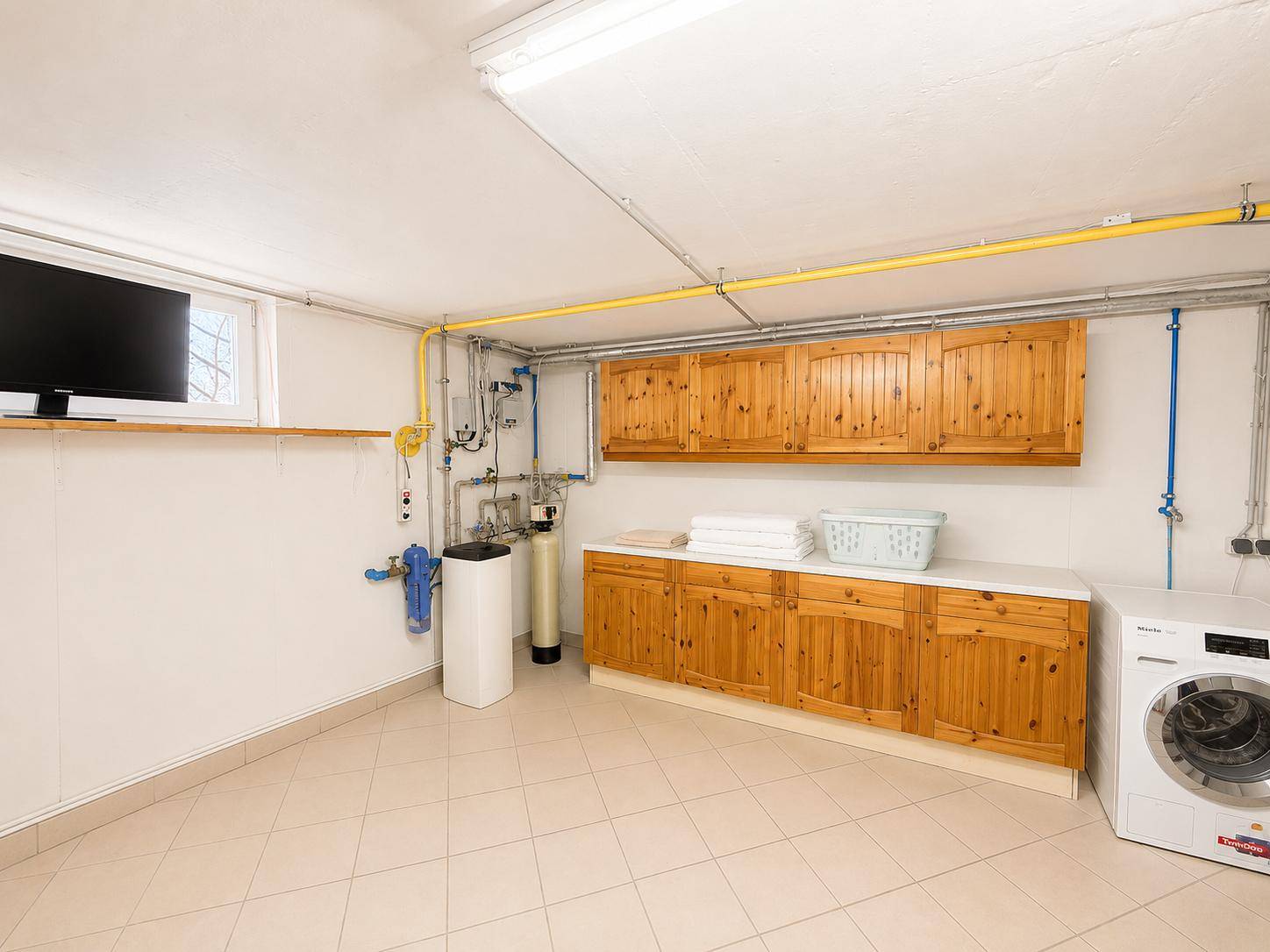 Praktischer Hauswirtschaftsraum mit Waschmaschine, Spüle und Holzschränken, ideal für den Alltag.