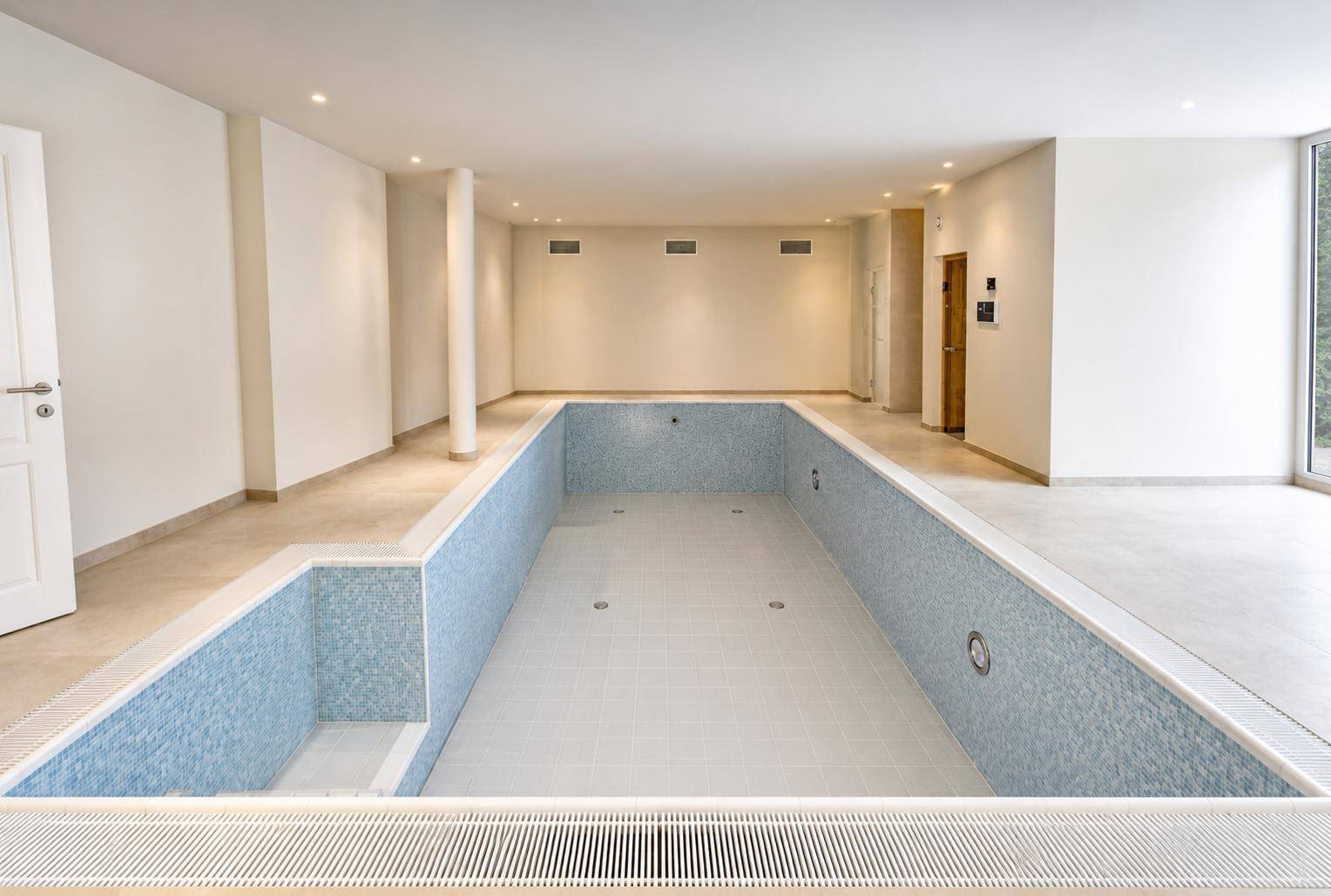 Geräumiger Innenbereich mit leerem Schwimmbecken, bereit für die Fertigstellung und Nutzung als Sportanlage.