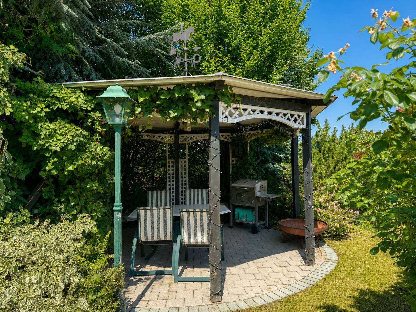 Idyllischer Gartenpavillon mit Sitzgruppe und Grill, perfekt für entspannte Stunden im Freien.