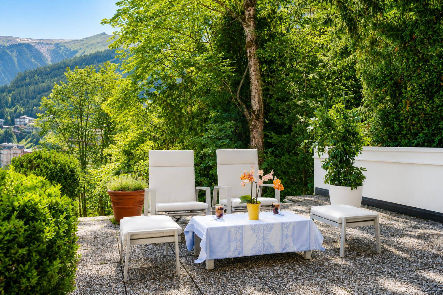 Sonniger Terrassenbereich mit Gartenmöbeln und Blick auf die grüne Berglandschaft.