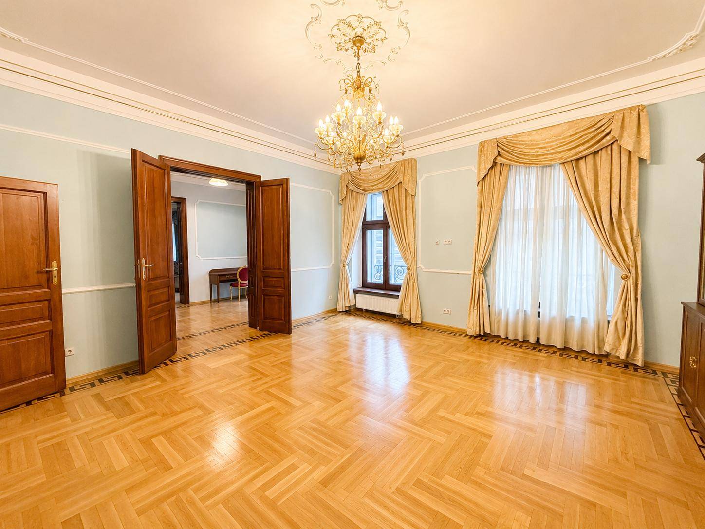 Geräumiges Zimmer mit Parkettboden, hohen Decken und großen Fenstern, bereit zur individuellen Gestaltung.