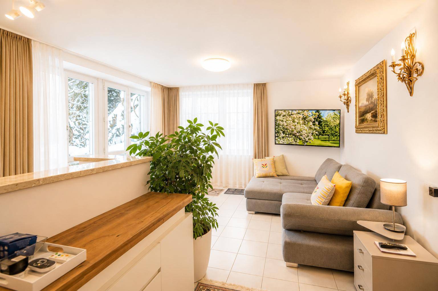 Heller Wohnbereich mit Sofa, Esstisch und Blick auf die verschneite Winterlandschaft.