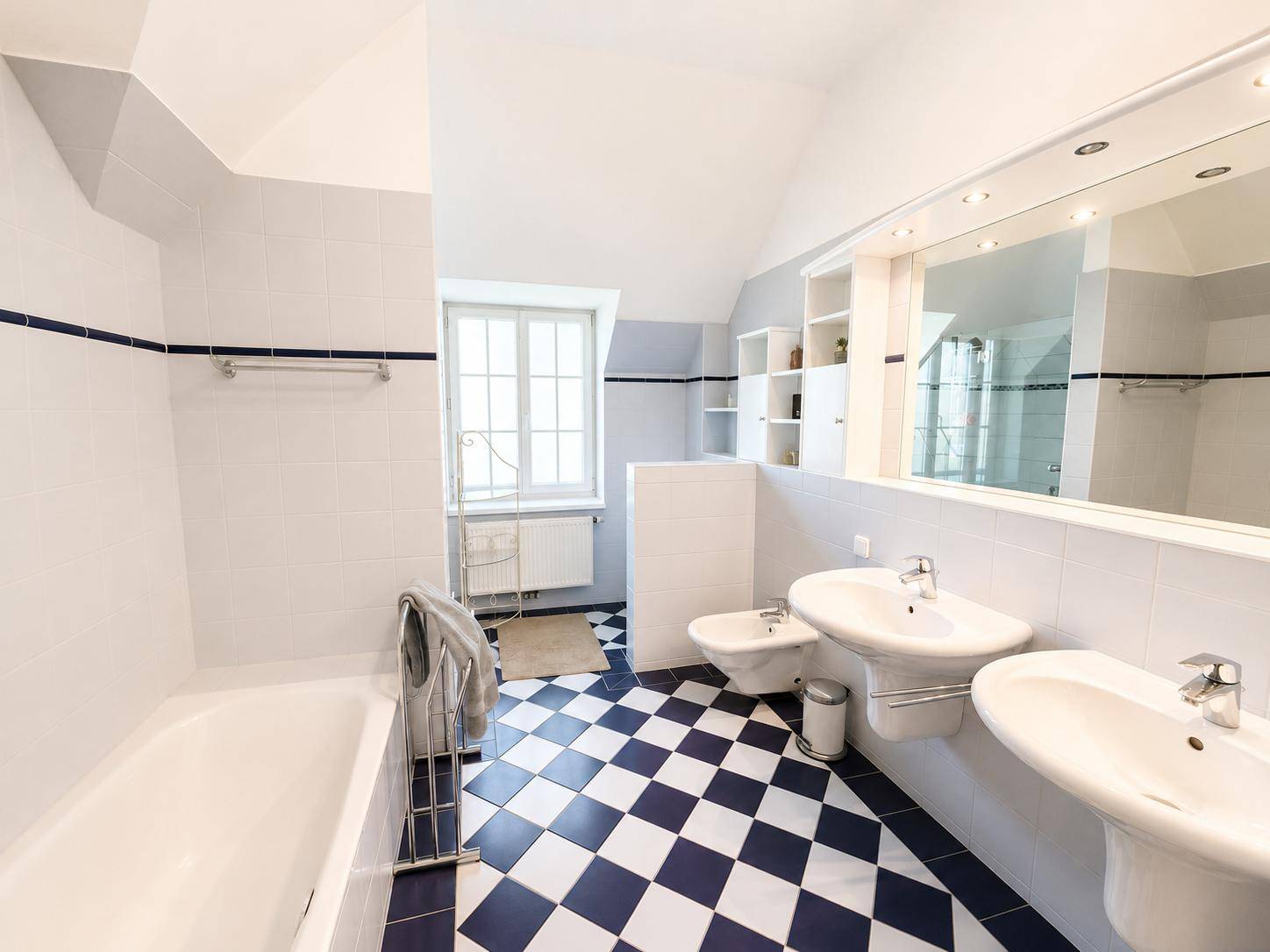 Geräumiges Badezimmer mit Doppelwaschbecken, Bidet und markanten blau-weißen Fliesen.