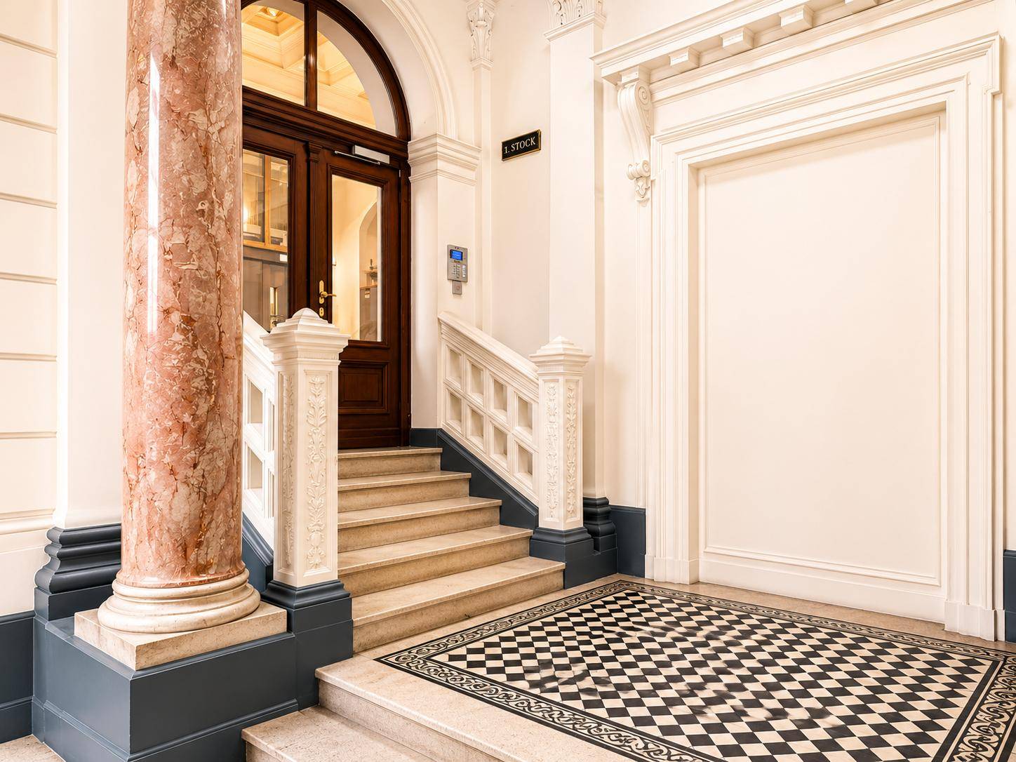 Repräsentatives Treppenhaus mit Marmorsäule, Schachbrettmuster-Fliesen und elegantem Geländer.