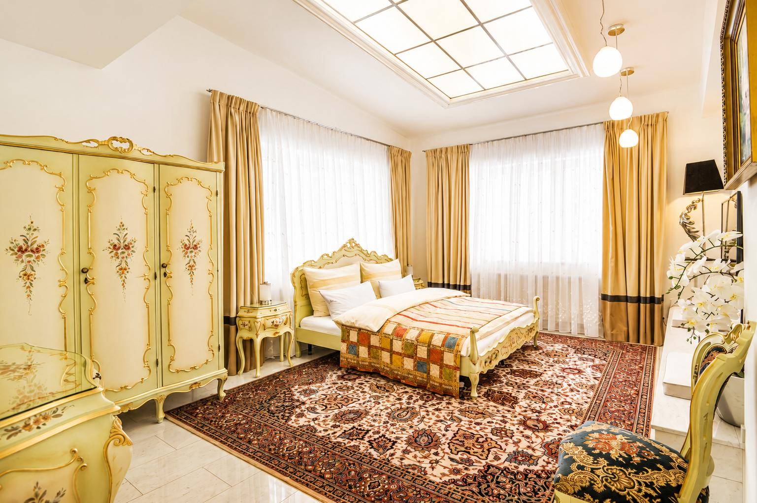 Geräumiges Schlafzimmer mit klassischem Dekor, großem Teppich und indirekter Deckenbeleuchtung.