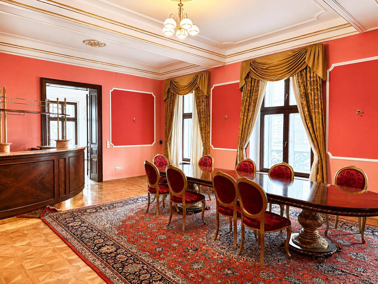 Prächtiges Esszimmer mit roten Wänden, großem Holztisch und passenden Stühlen auf einem Teppich.