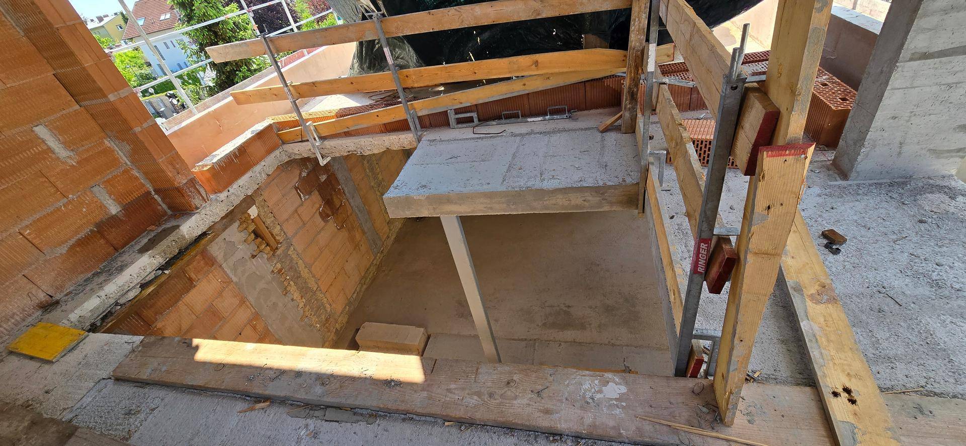 Baustellenbereich mit Treppenöffnung und unfertigen Betonstrukturen.