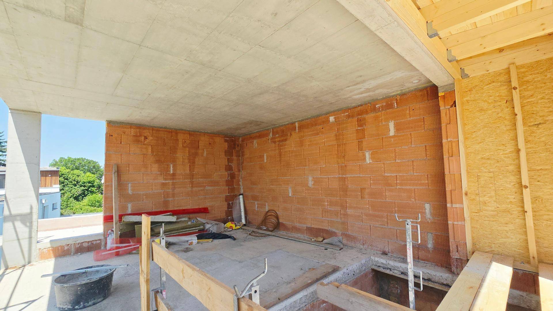 Rohbau eines Innenraums mit Ziegelwänden und Holzkonstruktion.
