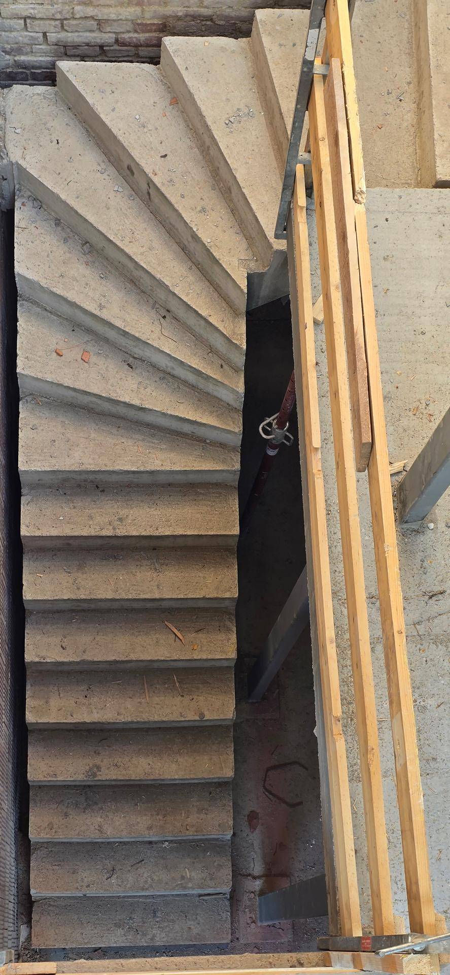 Wendeltreppe aus Beton im Rohbau, die verschiedene Stockwerke des Gebäudes miteinander verbindet.