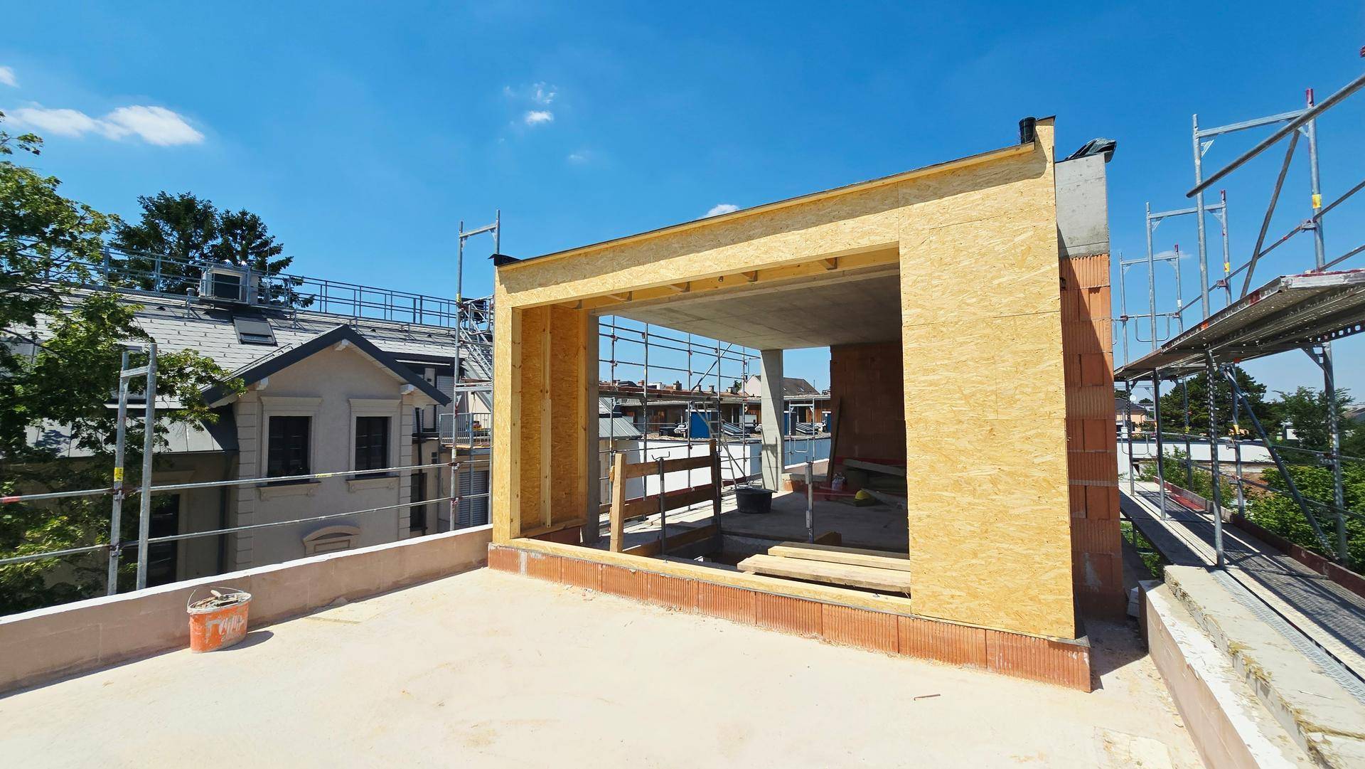 Dachgeschoss im Rohbau mit Holzrahmenkonstruktion und Blick auf die Umgebung.