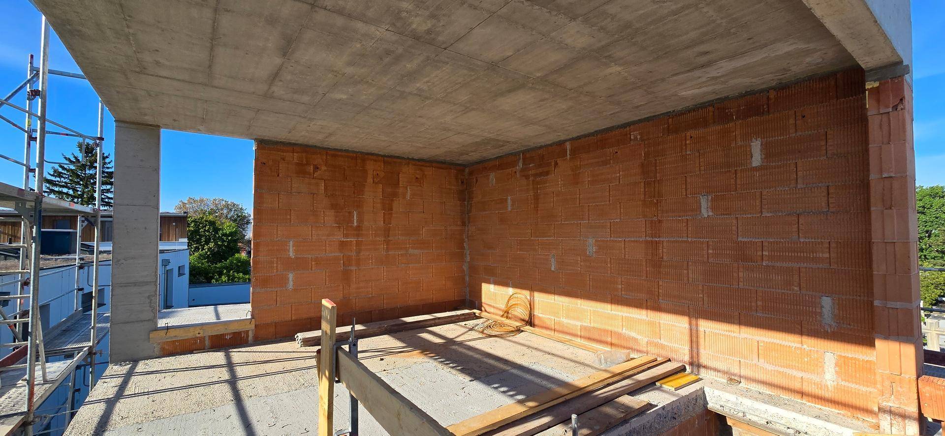 Innenansicht eines Rohbaus mit unverputzten Ziegelwänden und Betondecke, bereit für den weiteren Ausbau.