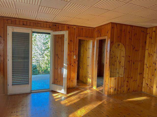 Gemütlicher Raum mit Holzverkleidung, Holzboden und Zugang zu einem Außenbereich.