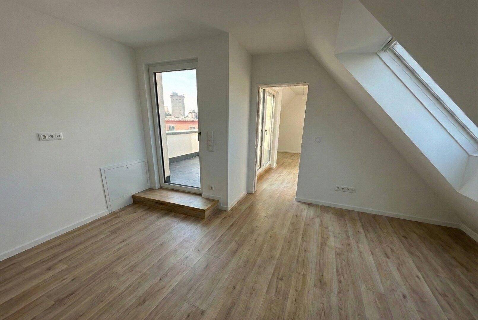 Lichtdurchfluteter Dachgeschossraum mit Zugang zu einer Terrasse und einem großen Dachfenster.