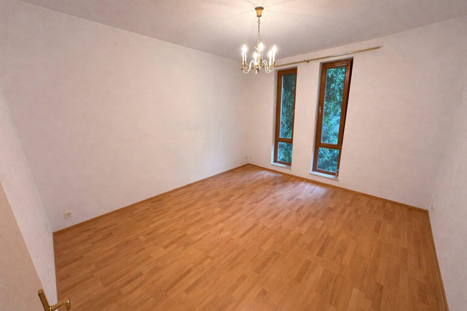 Ruhiges Zimmer mit Parkettboden und hohen Fenstern, ideal als Schlaf- oder Arbeitszimmer.