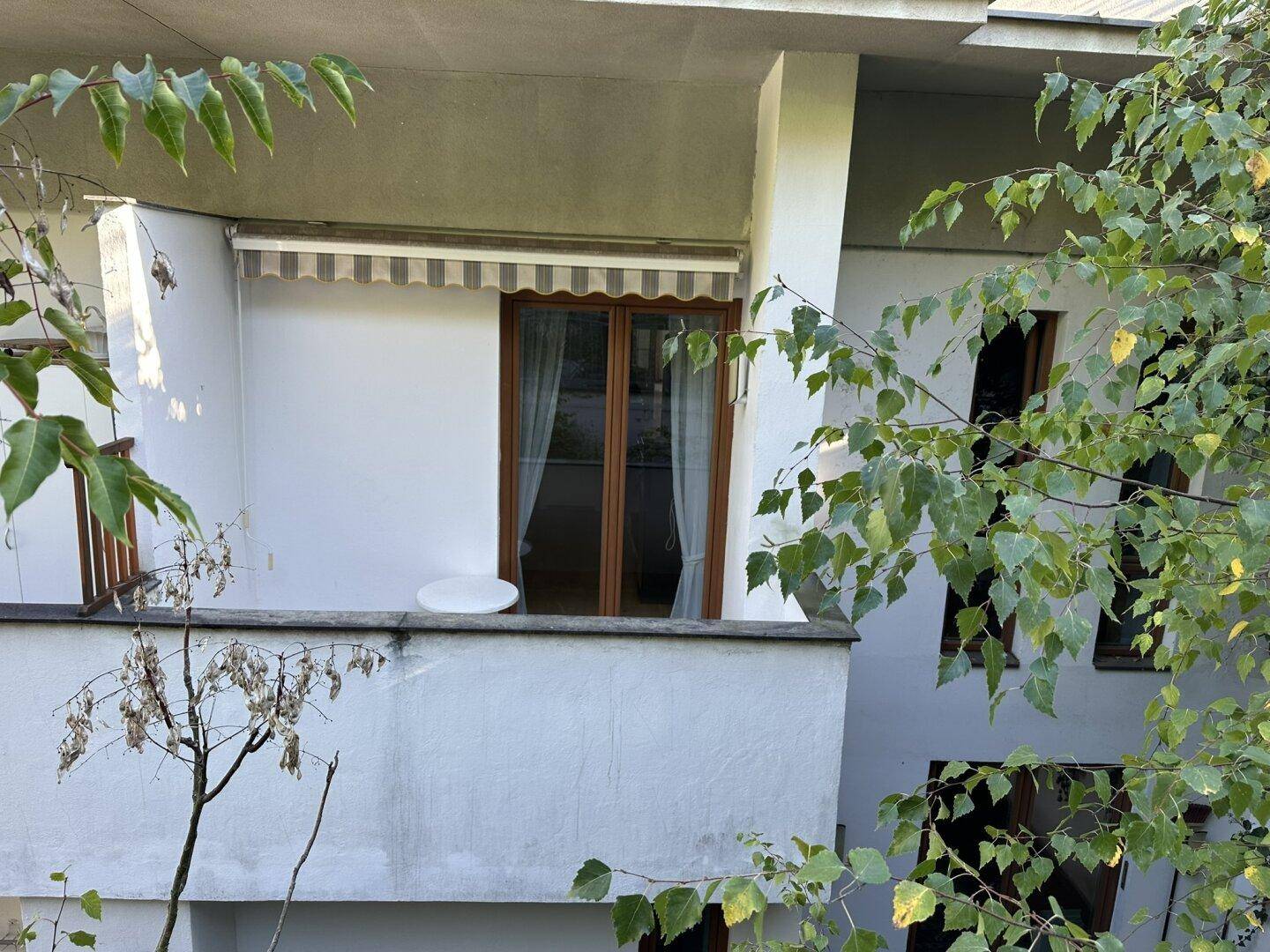 Kleiner Balkon mit Markise und Blick ins Grüne, ideal für entspannte Stunden.