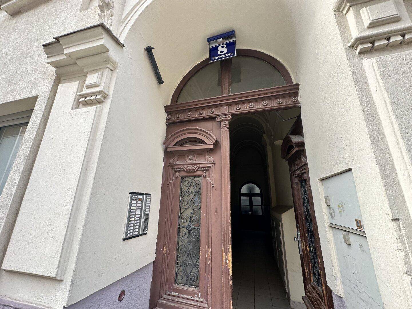 Historischer Hauseingang mit Holztür und dekorativen Elementen an der Fassade.