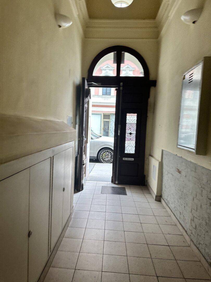 Eingangsbereich eines Altbaus mit Fliesenboden und Blick zur Haustür.