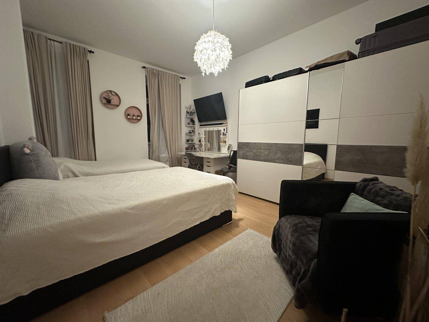 Gemütliches Schlafzimmer mit zwei Betten, Holzfußboden und einem großen Kleiderschrank.