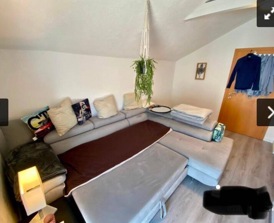 Geräumiges Wohnzimmer im Dachgeschoss mit großem Sofa und moderner Dekoration.