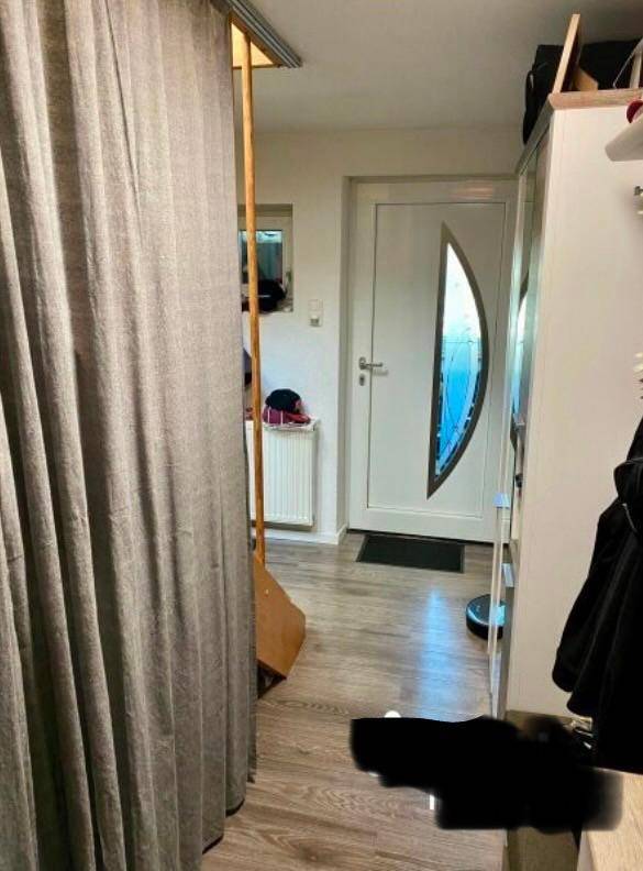 Eingangsbereich mit Holzboden, weißer Tür und Garderobe.