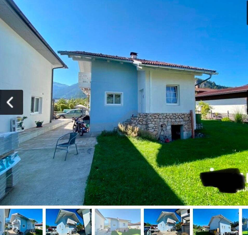 Rückseite des Hauses mit Rasenfläche, Steinfundament und Zugang zum Keller.