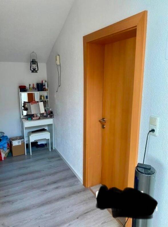 Bereich mit Schminktisch und Holztür in einem Zimmer mit Dachschräge.