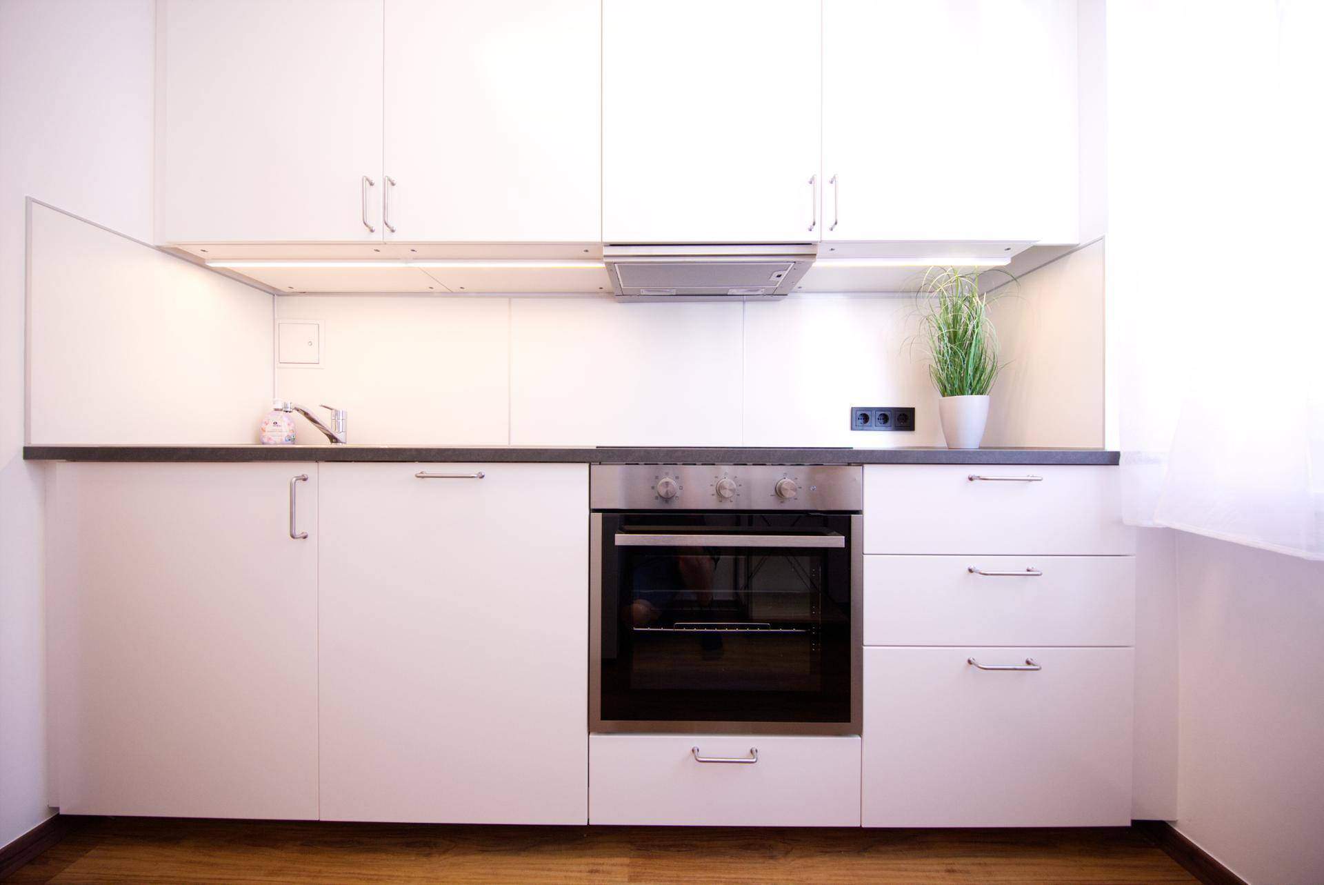 Moderne Einbauküche mit weißen Hochglanzfronten, Backofen und Dunstabzugshaube, sehr gepflegt.