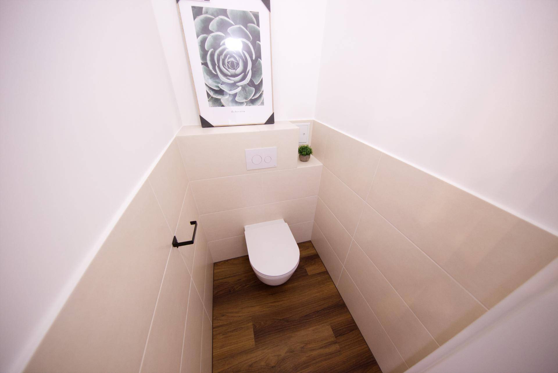 Separates WC mit Wand-WC und Fliesen an den Wänden, sauber und funktional.