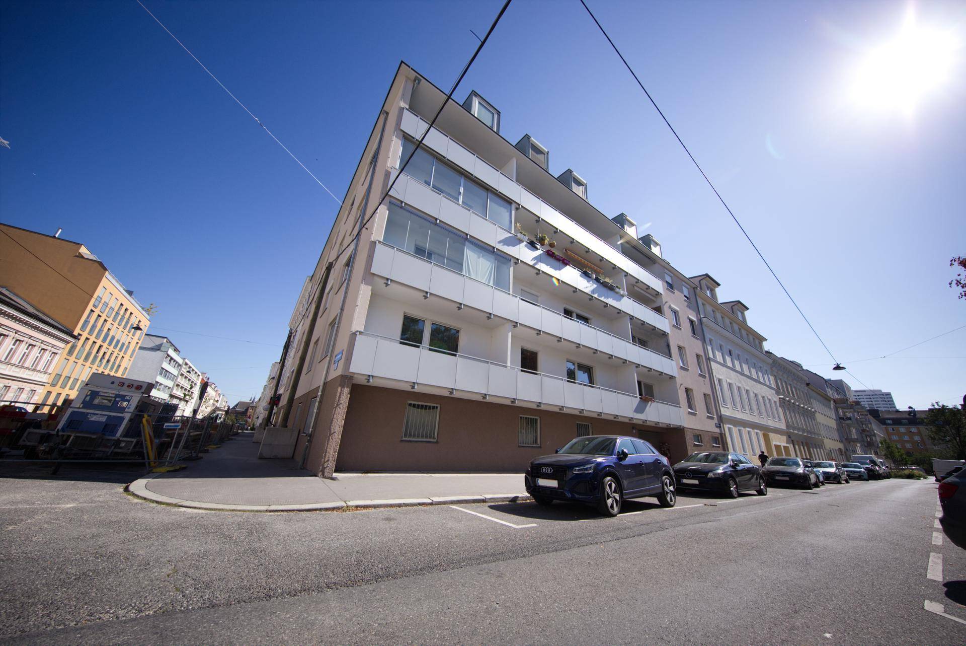 Modernes Mehrfamilienhaus mit Balkonen an einer sonnigen Straße, in guter Lage.