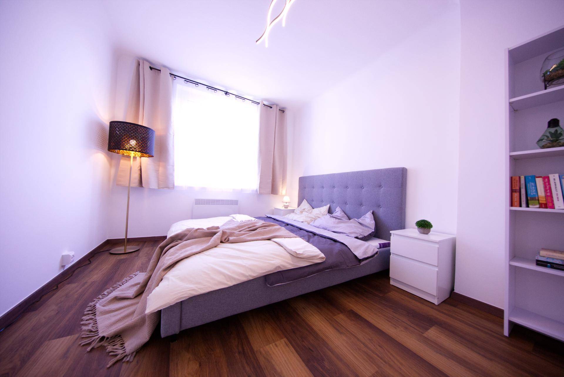 Helles Schlafzimmer mit großem Fenster, Doppelbett und Nachttisch, bietet viel Komfort.
