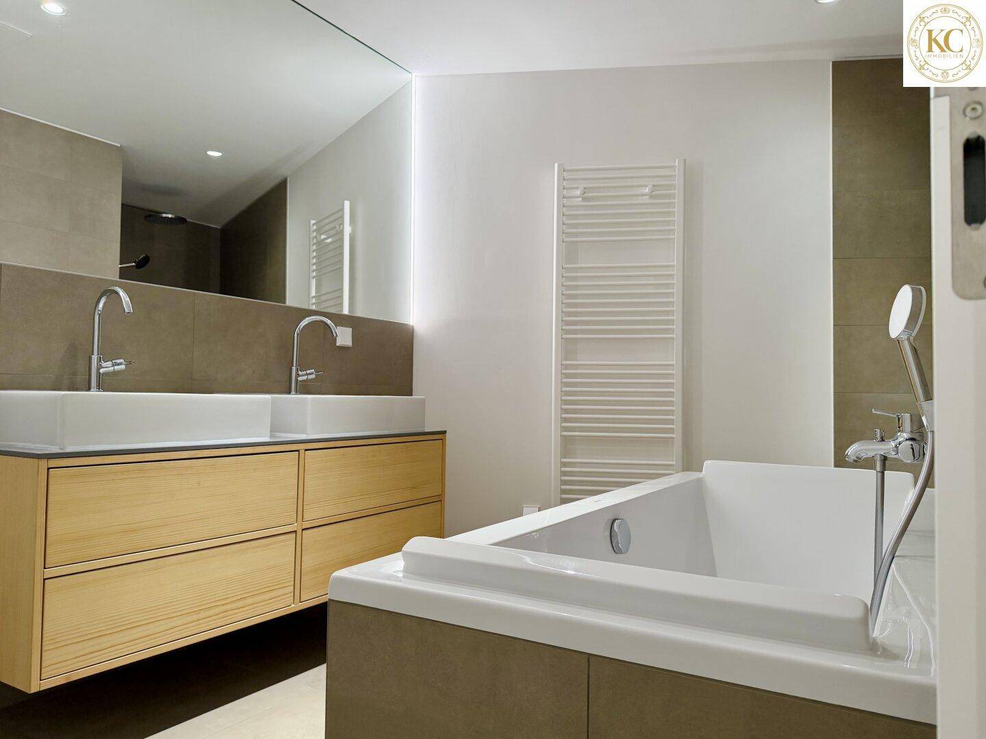 Modernes Badezimmer mit Doppelwaschbecken, Badewanne und beheiztem Handtuchhalter.