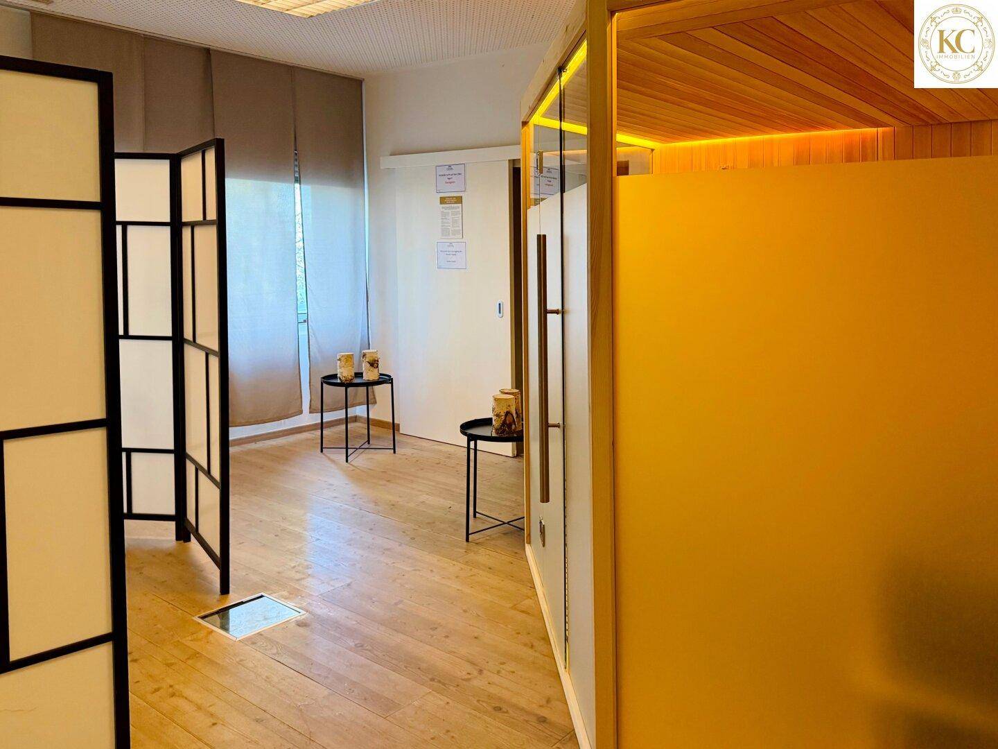 Heller Flurbereich mit Holzboden, der zu einem Wellnessbereich mit Sauna führt.