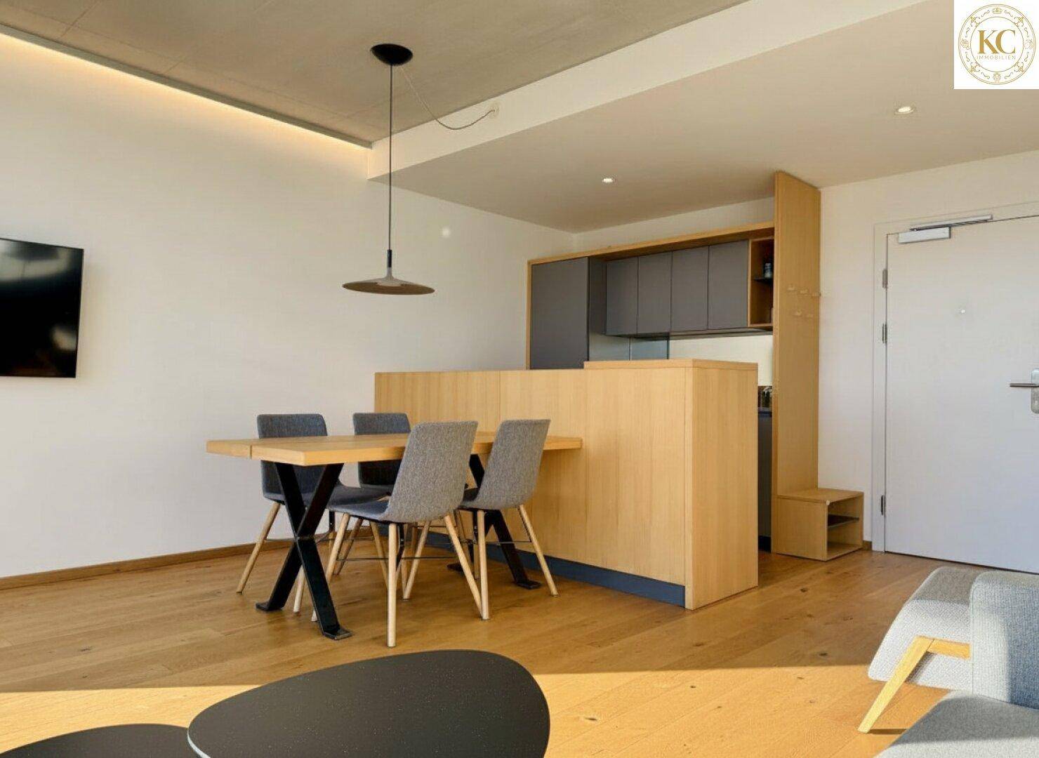 Heller Essbereich mit modernem Tisch und Stühlen, angrenzend an eine halboffene Küche.