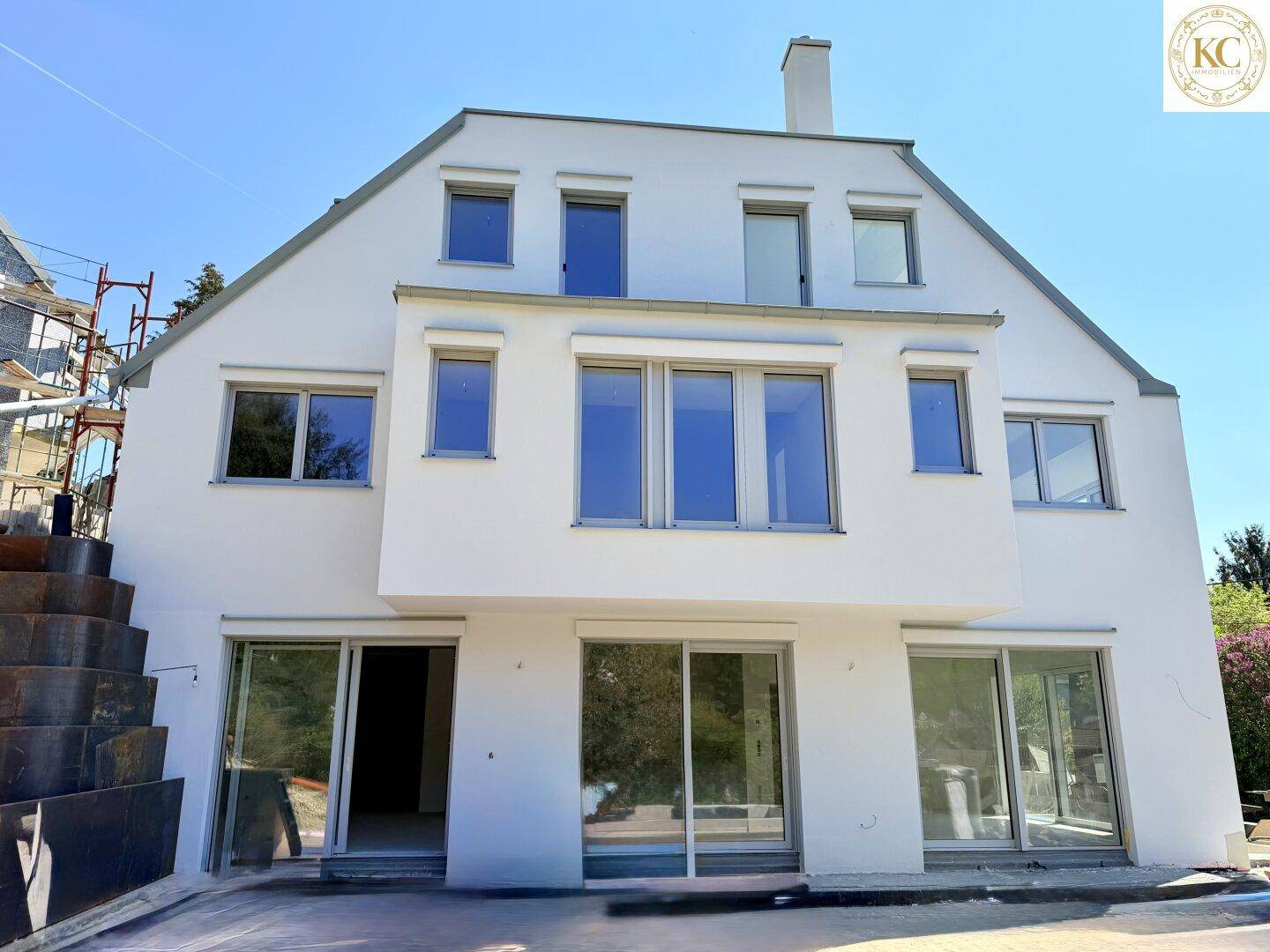 Rückseite des Neubaus mit großen Fensterfronten und Schiebetüren zum Gartenbereich.