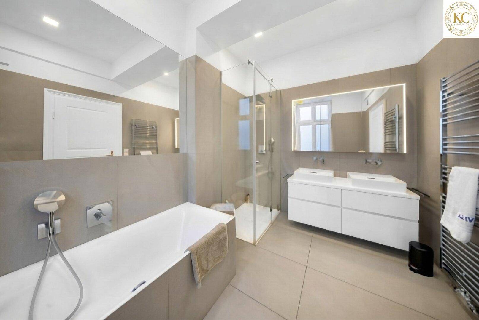 Modernes Badezimmer mit Badewanne, Duschkabine, Doppelwaschbecken und großen Fliesen.