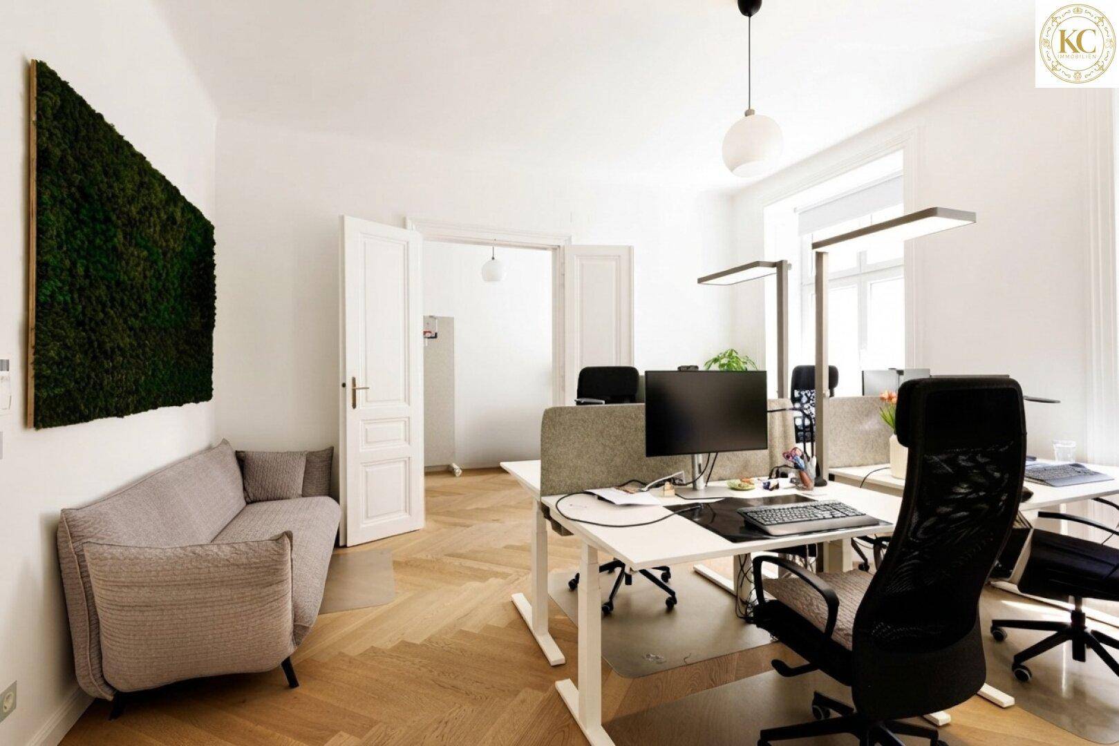 Modernes Büro mit Schreibtischen, ergonomischen Stühlen und einer Mooswand als Dekoration.