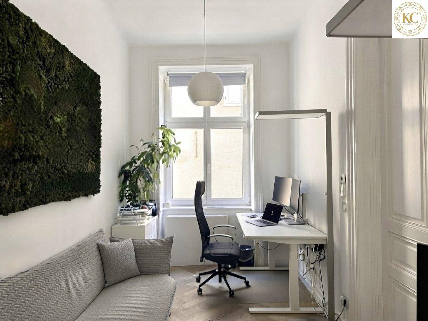 Kleineres Büro mit Schreibtisch, ergonomischem Stuhl, Sofa und einer grünen Mooswand.