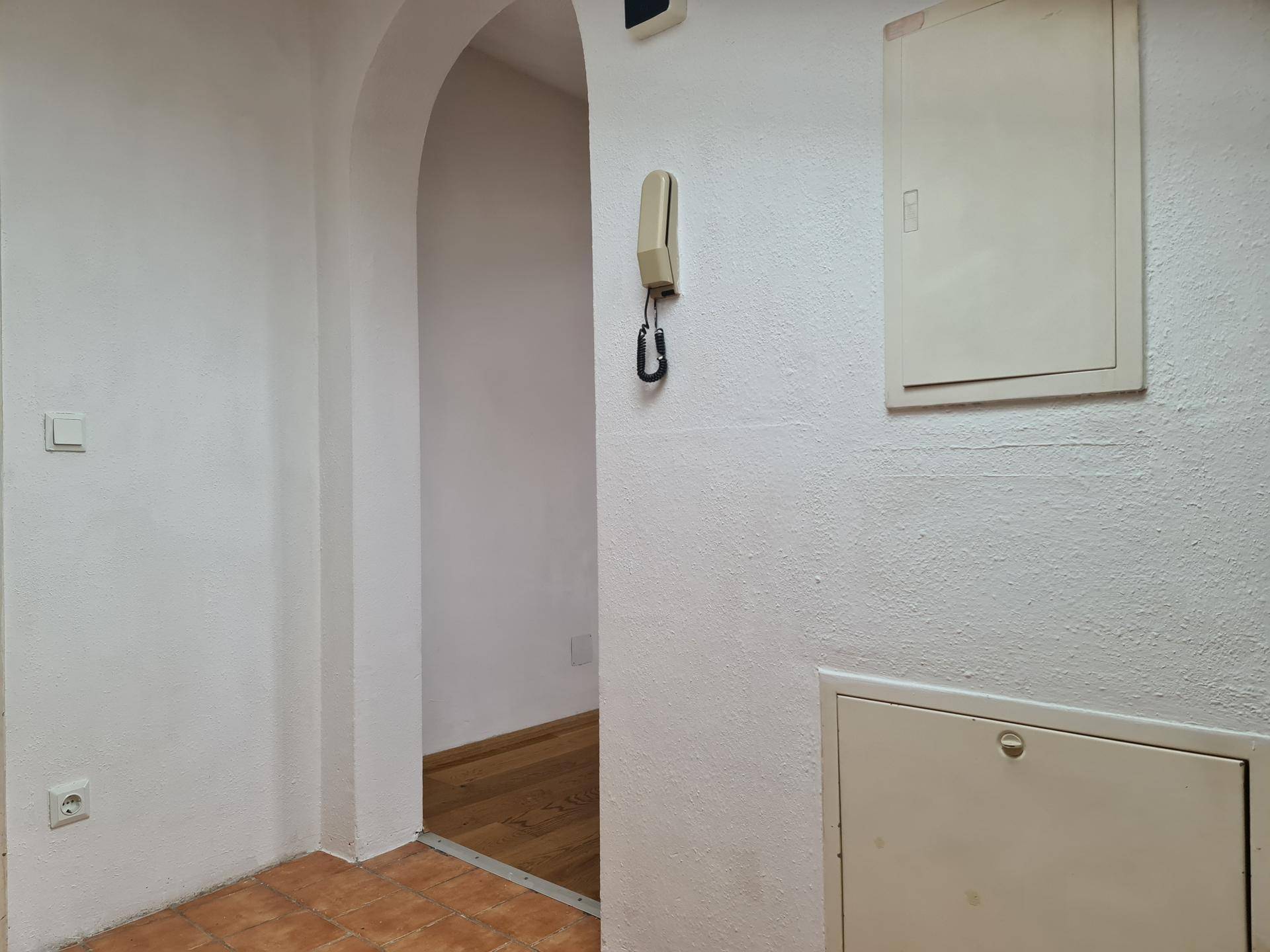 Heller Flur mit Terrakotta-Fliesen und Gegensprechanlage.