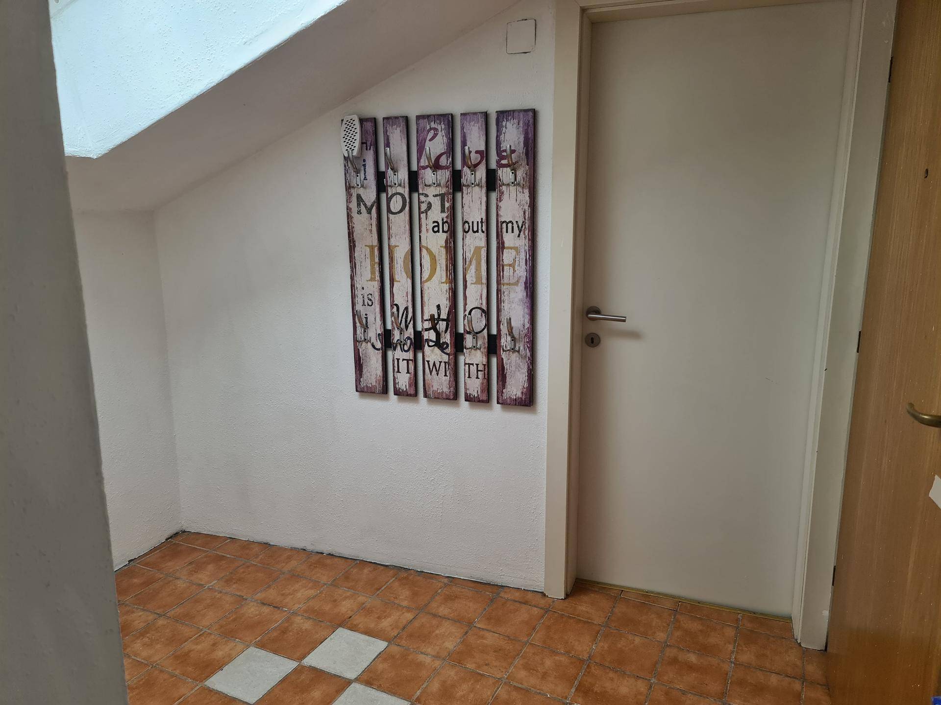 Eingangsbereich mit Terrakotta-Fliesen und dekorativem Wandbild.