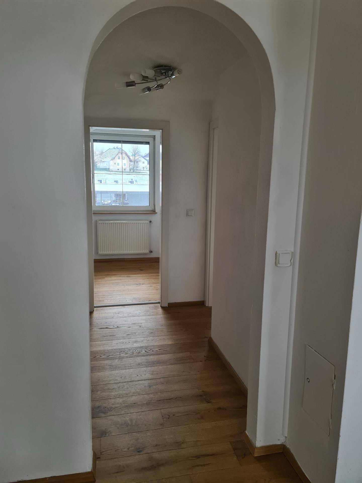Heller Flur mit Holzboden und Rundbogen, der zu weiteren Zimmern führt.