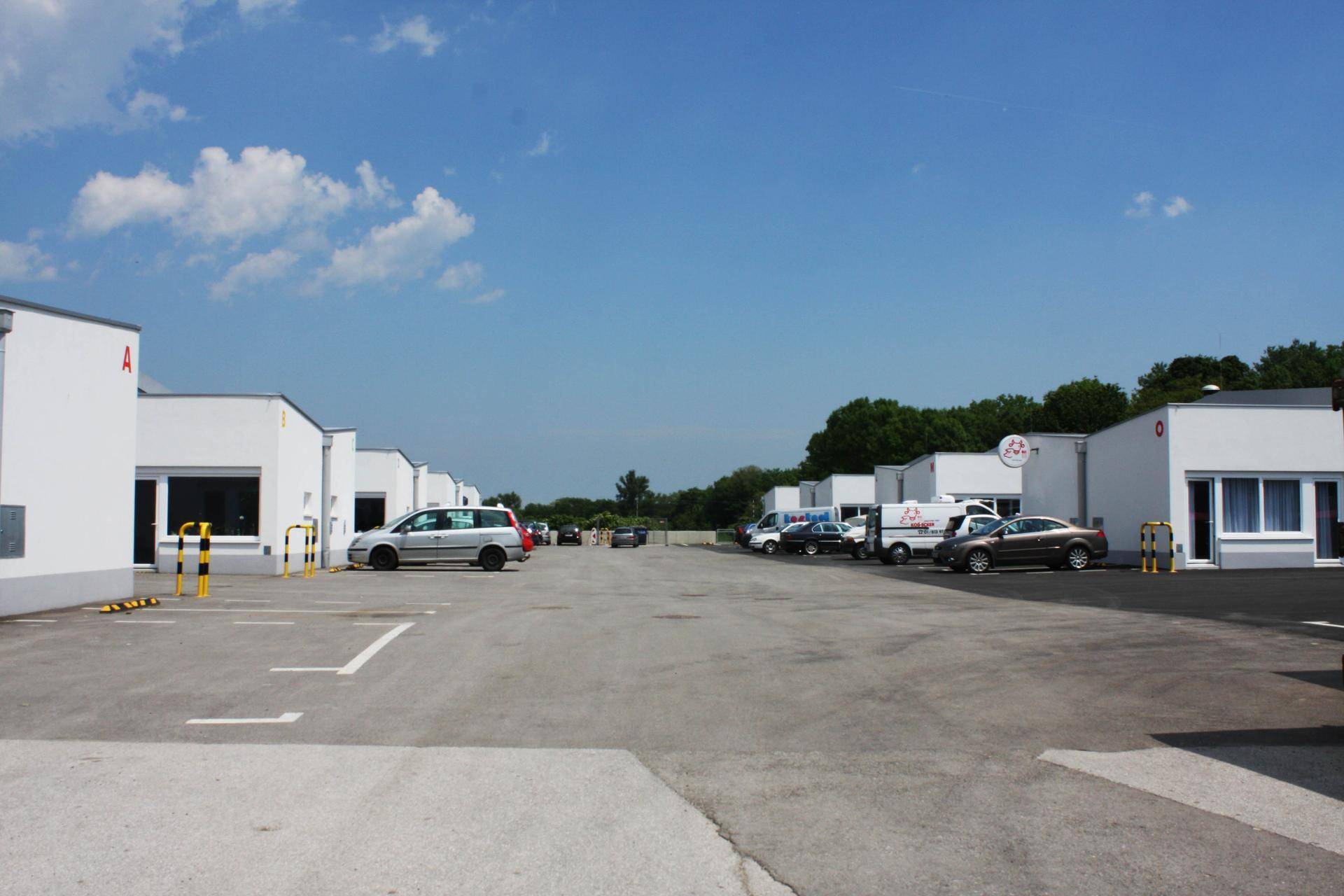 Weitläufige Außenansicht eines Gewerbeparks mit mehreren weißen Gebäuden und großem Parkplatz.