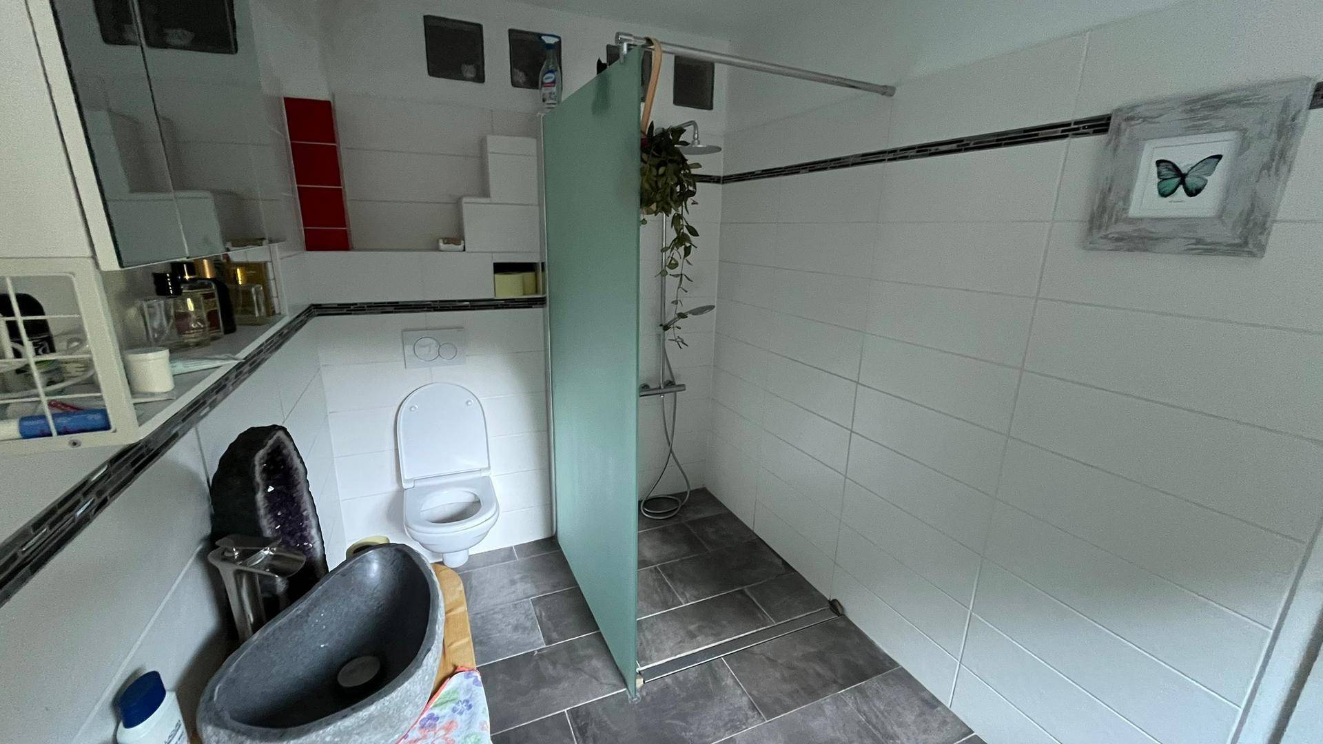 Funktionales Badezimmer mit Duschbereich, WC und modernem Steinwaschbecken für den täglichen Komfort.