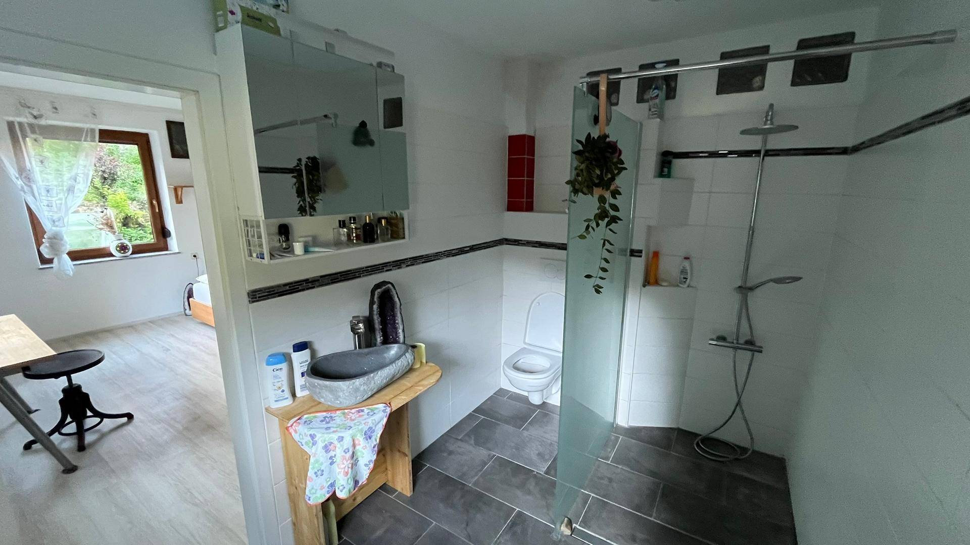 Modernes Badezimmer mit ebenerdiger Dusche, Steinsink und dunklen Bodenfliesen für den täglichen Gebrauch.