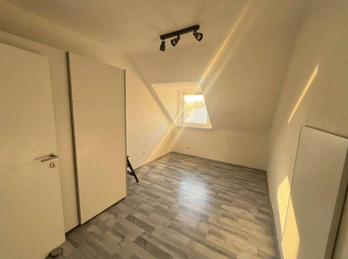 Helles Schlafzimmer im Dachgeschoss mit Laminatboden, Einbauschrank und schrägen Wänden.