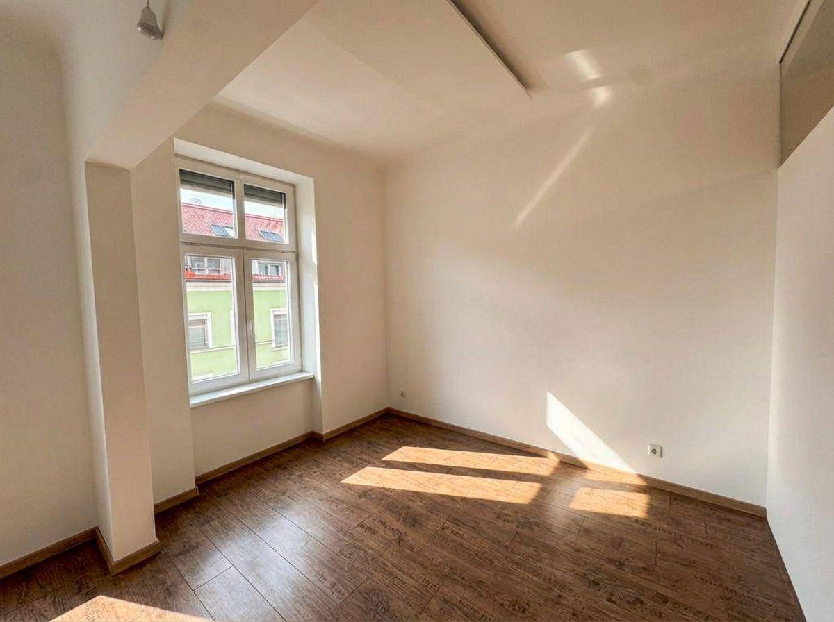 Helles Schlafzimmer mit Holzboden und einem Fenster, das eine angenehme Atmosphäre schafft.